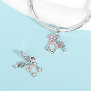 Detalle de dijes de música en plata con micrófono retro y auriculares rosas con circonitas