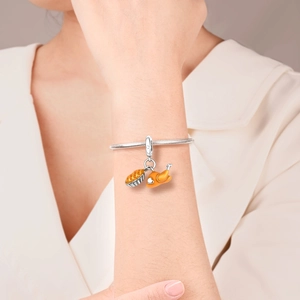 Dettaglio del bracciale con ciondoli a forma di tacchino arrosto e torta all'arancia