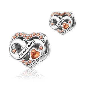 Detailed macro view of heart-shaped silver charm with amber stone and loyal engraving