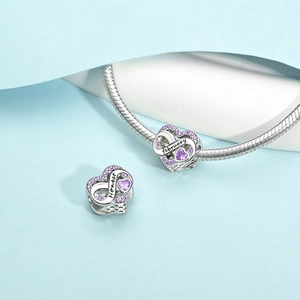 Macro detail of silver heart charm with purple stones, infinity symbol and Honest engraving