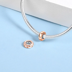 Macro detail of rose gold spacer beads on a silver snake chain bracelet for jewelry DIY