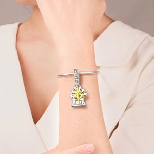 Nahaufnahme eines zweifarbigen religiösen Kreuzanhängers mit Zirkonia am Silberarmband
