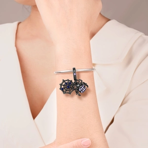 Detail of black spider and web charm pendant with purple zircons on silver snake chain