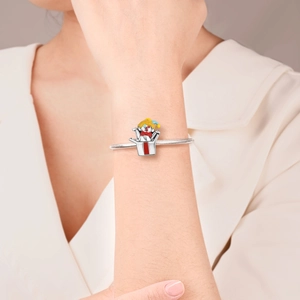 Detail of silver snake chain bracelet featuring a colorful enamel Jack-in-the-box charm