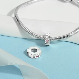 Detailed view of silver-plated copper LOVE charm with pink zircon on snake chain bracelet