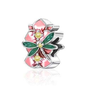 Macro detail of enamel flower charm with green dragonfly and yellow zircon inlay