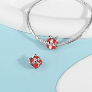 Detailed view of red enamel gift box charm with pink heart zircon on a silver bracelet
