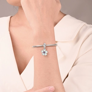 Close-up of a silver snake chain bracelet featuring a floral pendant with opal-like petals