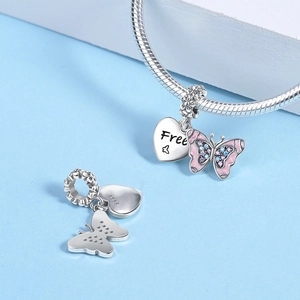 Macro shot of silver butterfly heart charm with pink enamel and engraved Free script