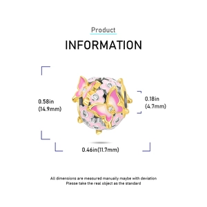 Macro detail of golden butterfly charm with pink enamel and white cubic zirconia