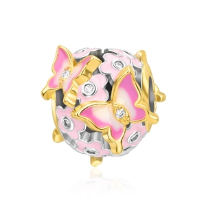 Macro shot of silver and gold charm with pink butterfly and sparkling stones
