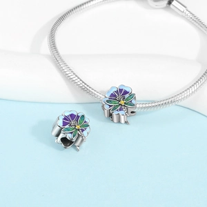 Close-up of a silver dragonfly and flower charm bracelet with enamel and zircon details