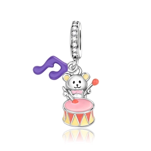 Detalle de un dije de plata con un oso tocando el tambor, esmalte colorido y circonitas