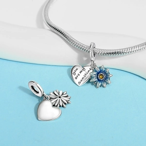 Macro view of silver dragonfly charm with 'You are my sunshine' engraving and enamel flower