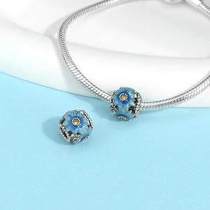 Detailed macro view of blue enamel flower charm with yellow zircon on a silver chain