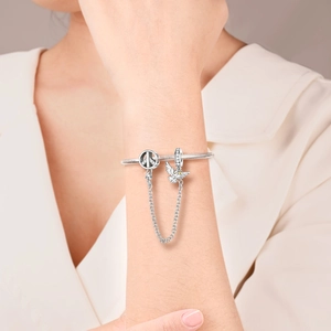 Detalle de cadena de seguridad con dijes de paz y paloma en pulsera de cadena de serpiente