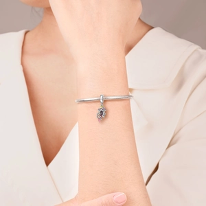 Detailed view of silver snake chain bracelet with purple and pink zircon jellyfish pendant