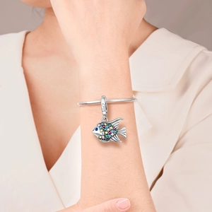 Macro detail of a tropical fish charm with colorful zircons on a silver bracelet