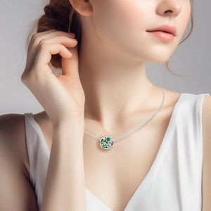 Close-up of silver necklace featuring a clover charm with green enamel and white crystals