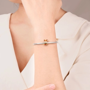 Detail of silver snake chain bracelet featuring a colorful enamel reindeer charm
