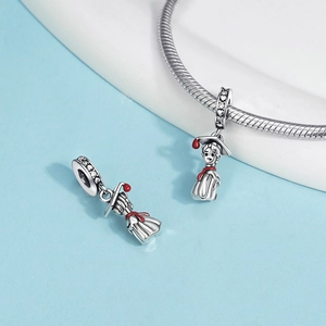 Macro shot of silver graduation charm with red enamel cap and sparkling zircon inlay
