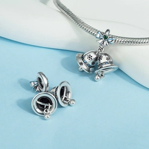 Detailed view of silver bell charms with blue snowflake engravings and green heart stone