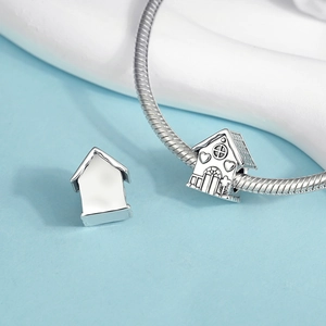 Macro view of a silver house charm with heart detail on a snake chain bracelet