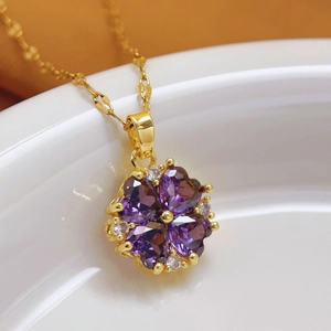 Dettaglio macro del ciondolo a quadrifoglio in oro 18K con pietre viola e zirconi