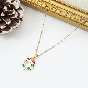 Macro detail of Christmas wreath pendant with red bow and green enamel on gold chain