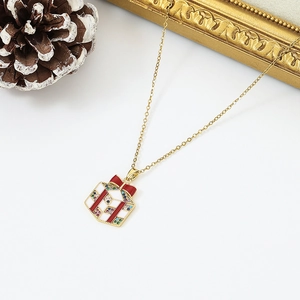 Close-up of golden Christmas gift box pendant with red enamel ribbon and colorful zircons