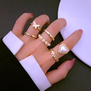 Detail von 6-teiligem Goldring-Set mit Schmetterling und Herzperle an der Hand