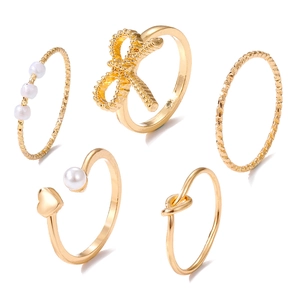 Détails d'un ensemble de 5 bagues dorées avec perles, cœurs et nœud papillon délicat
