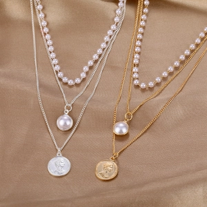 Elegant multi-layered gold and silver pearl necklace set with coin pendant on satin