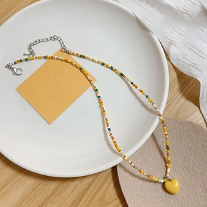 Gros plan d'un collier de perles colorées avec un pendentif coeur jaune sur une table