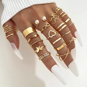 Detail van hand met 22-delige gouden ringenset met vlinder- en hartvormige bedels