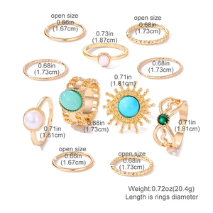 Set di 9 anelli vintage dorati con pietre color smeraldo e motivi boho su sfondo bianco