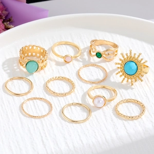 Set di 10 anelli bohémien dorati con pietre verde smeraldo e perle su vassoio bianco