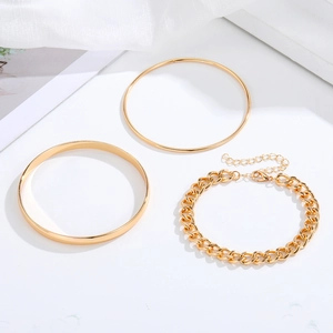 Ensemble de trois bracelets dorés avec chaînes serpent et cubaines sur tissu blanc
