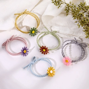 5-piece set of daisy flower hair ties on white fabric with greenery accents
