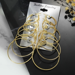 6 pairs set of gold hoop earrings with textured finish on elegant marble background