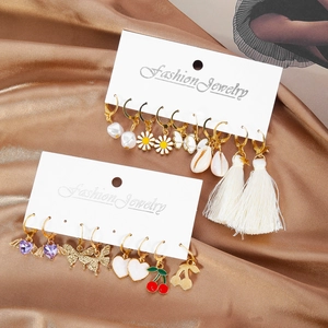 Set di orecchini alla moda con motivi a ciliegia, farfalla e margherita su sfondo satinato