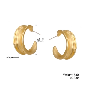 Détail de boucles d'oreilles créoles C dorées de 2,3 cm avec texture alliage martelé
