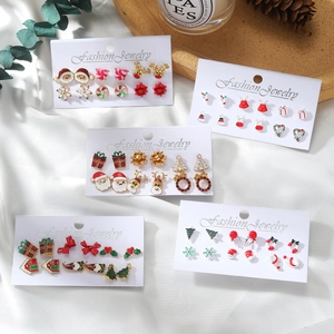 Set orecchini natalizi con Babbo Natale, renna e fiocchi di neve su carta bianca