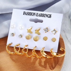 Set aus goldenen Ohrringen mit Perlen und Schmetterlingssteckern auf Karte