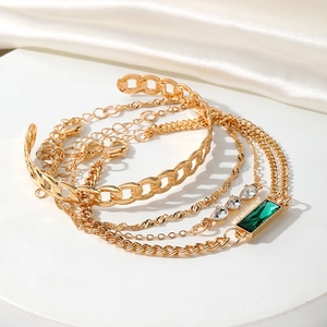 Set di bracciali dorati con cristalli verde smeraldo e dettagli di catena vintage