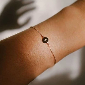 Rose gold chain bracelet featuring a round pendant with a personalized letter R