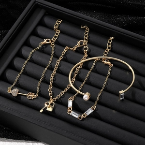Juego de 4 pulseras doradas con dijes de corazón, llave, candado y brazalete de perlas