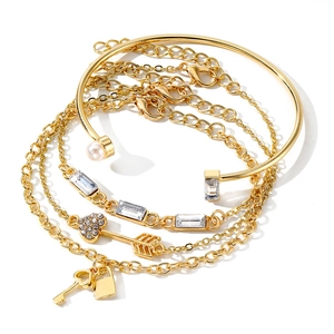 Detalle de un set de pulseras doradas con colgantes de candado, perlas y cristales
