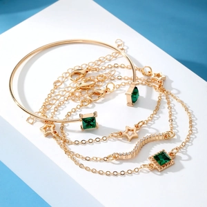 Detail of emerald square gemstones and star pendants on a golden 4-piece bracelet set