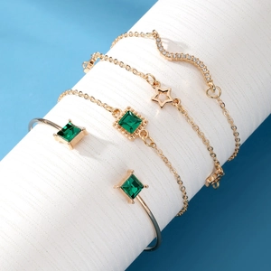 Set of 4 gold bracelets featuring emerald square gems, stars, and snake motifs for women